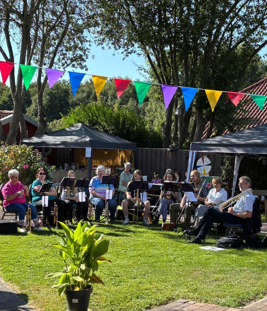 Bläserensemble mit Trompeten und Posaunen spielt im Halbkreis auf dem Rasen