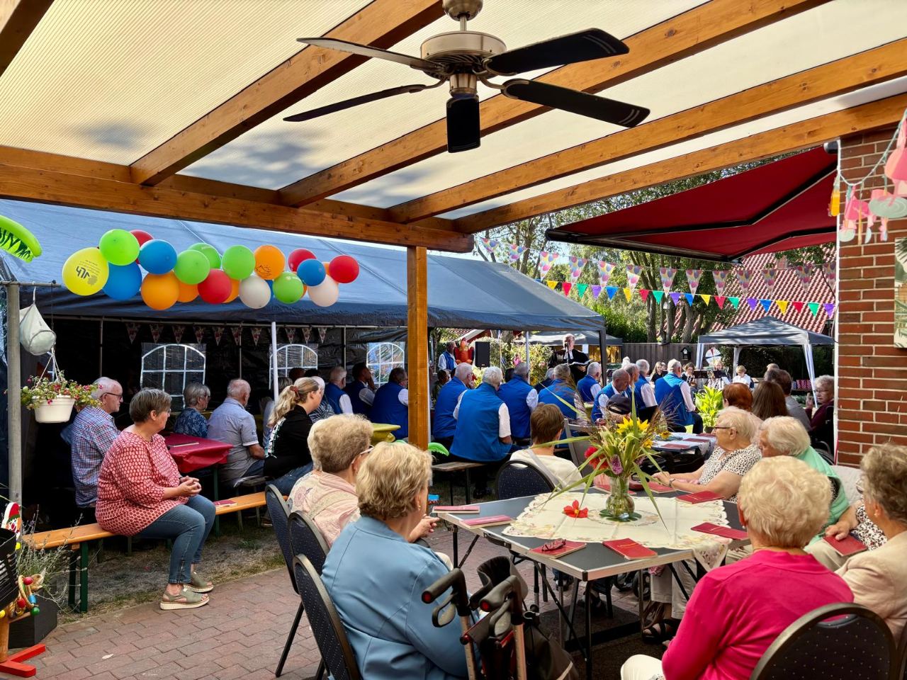 Volle Kaffeetafel unter der Pergola, darüber bunte Luftballons